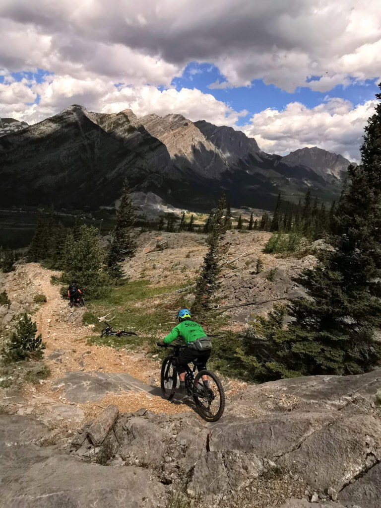 A mountain biker navigating a steep rock roll on the Razor's Edge trail.