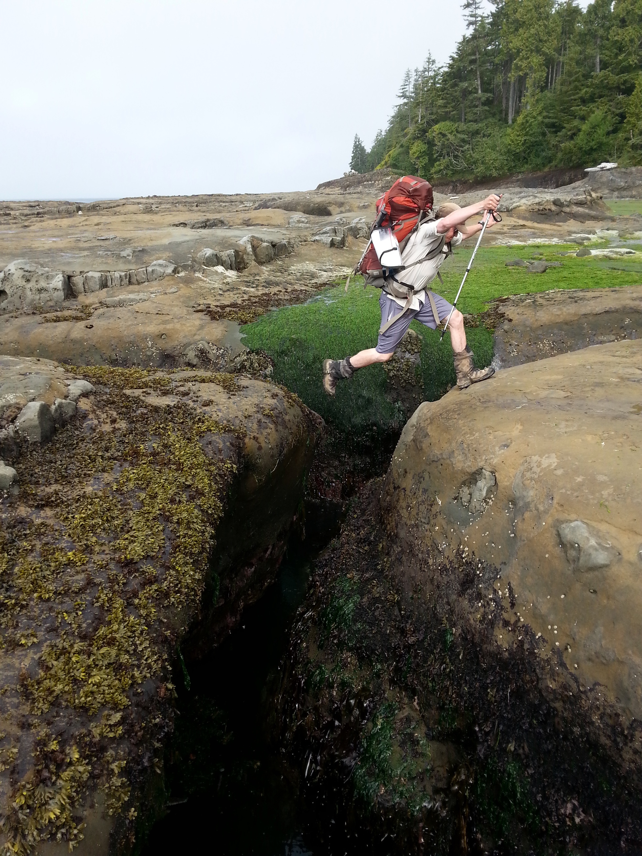 A hiker's boots on a rocky shoreline on the West Coast Trail.