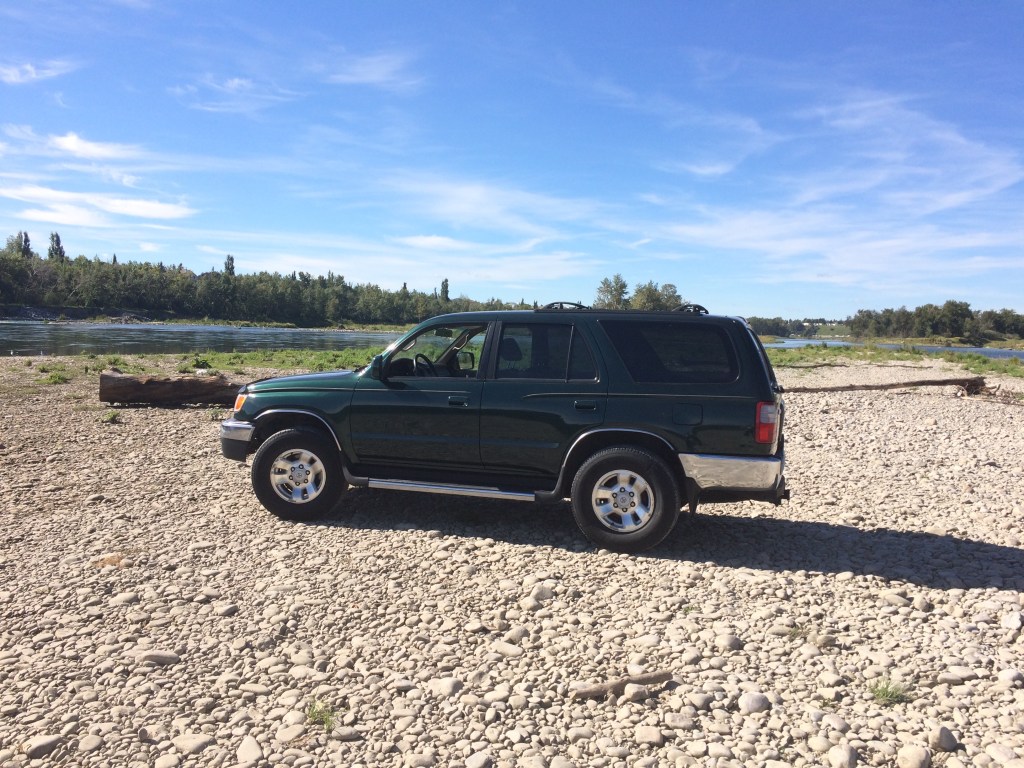 A green 3rd generation Toyota 4Runner parked on a gravel bar near the Bow River.